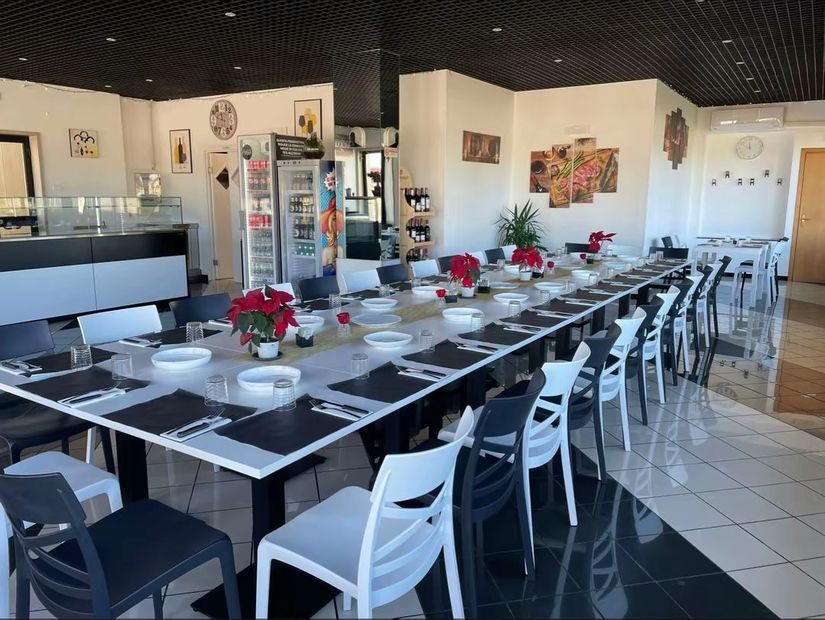 Sala da pranzo moderna con un lungo tavolo apparecchiato, sedie bianche e centrotavola di stelle di Natale rosse.