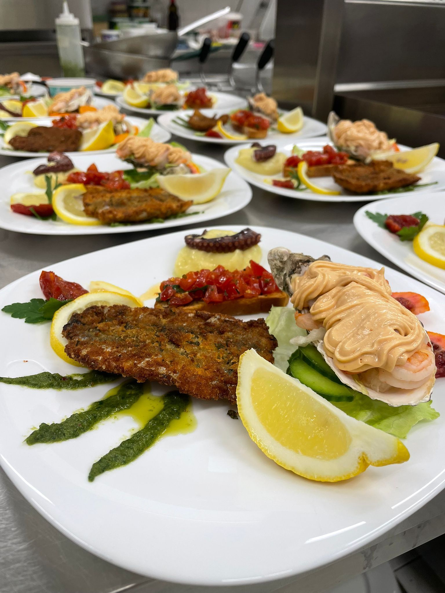 Piatti di pesce gourmet impiattati con spicchi di limone e guarnizione su un tavolo di ristorante.