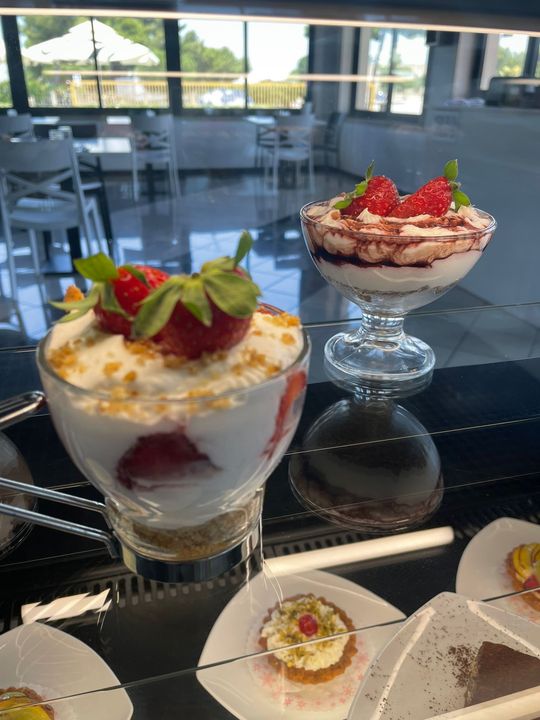 Dolci guarniti con fragole su un tavolino da caffè vicino a una finestra luminosa