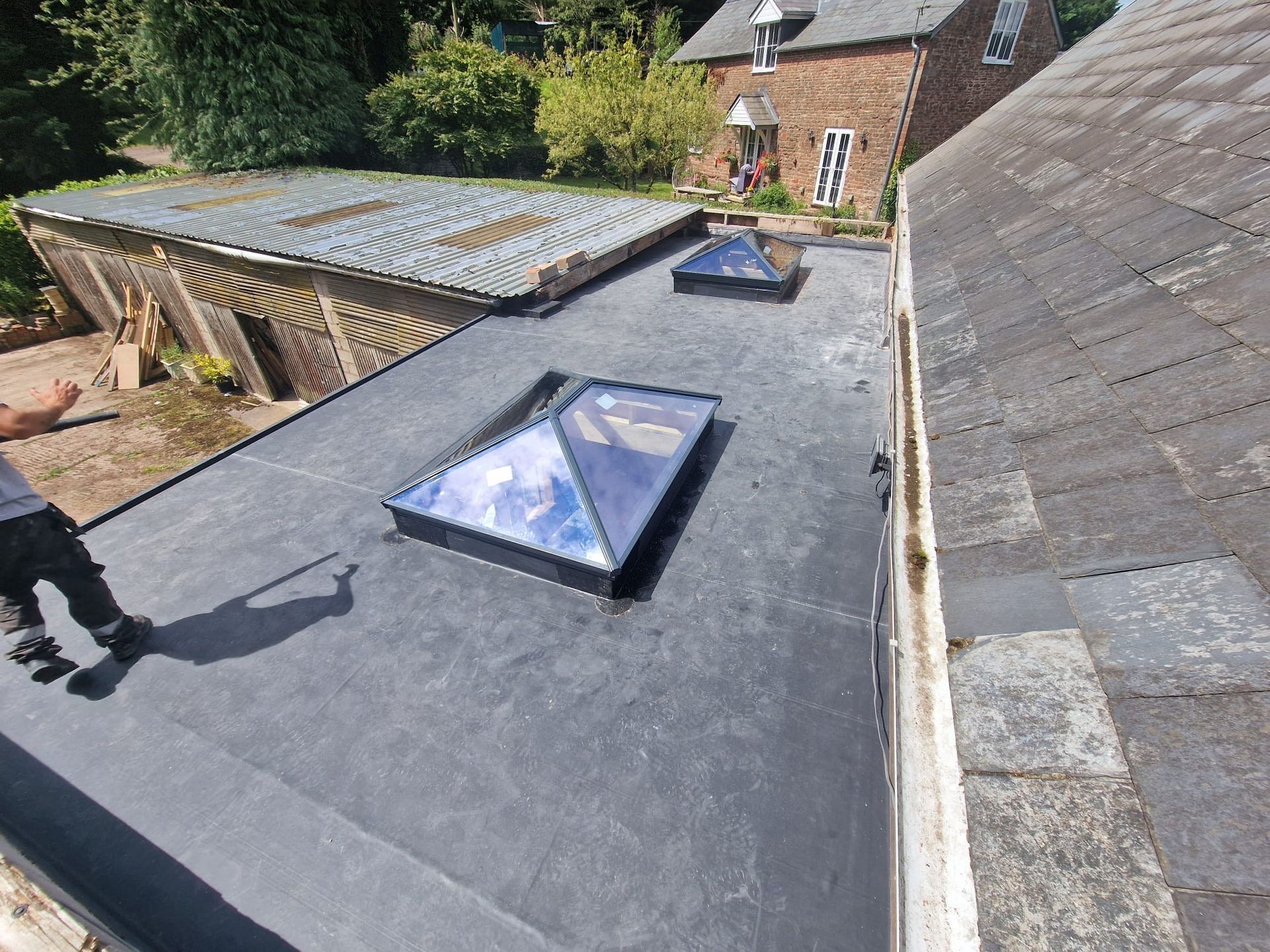 A skylight on the roof of a house with trees in the background.