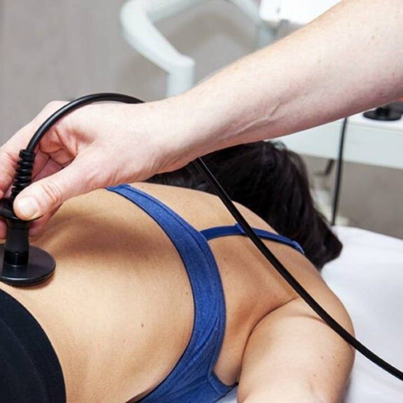 Persona sottoposta a terapia sdraiata sulla schiena, tenuta per mano; cavo nero ed elettrodo visibili.