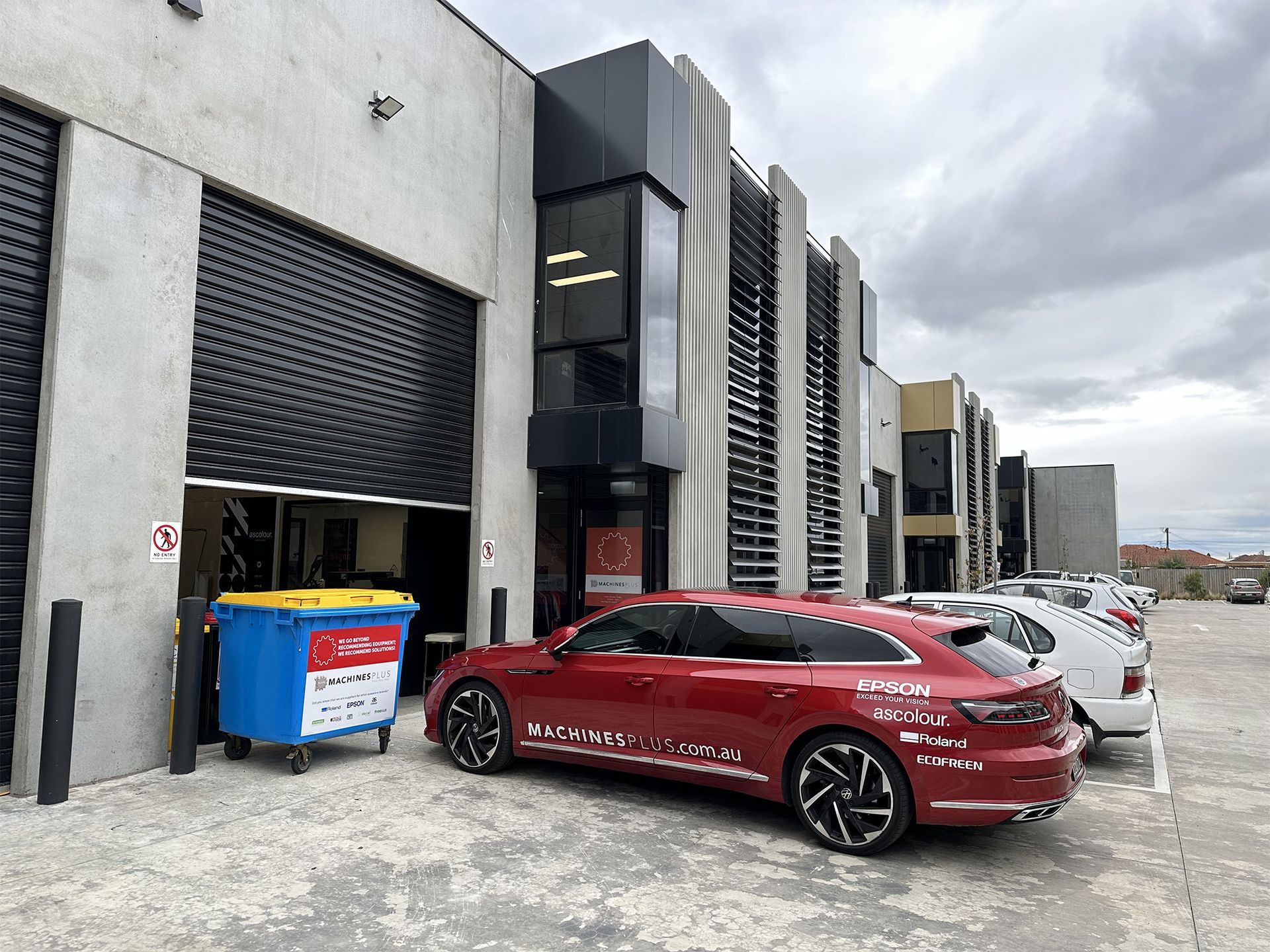 Machines Plus warehouse with red car parked out the front.