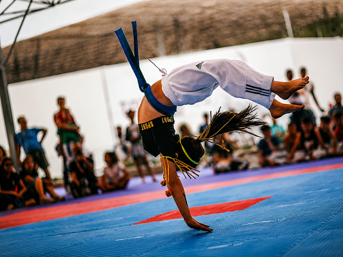 Persone che si allungano su tappetini da ginnastica durante una lezione di fitness, protendendosi in avanti con palle da stabilità dietro di loro.