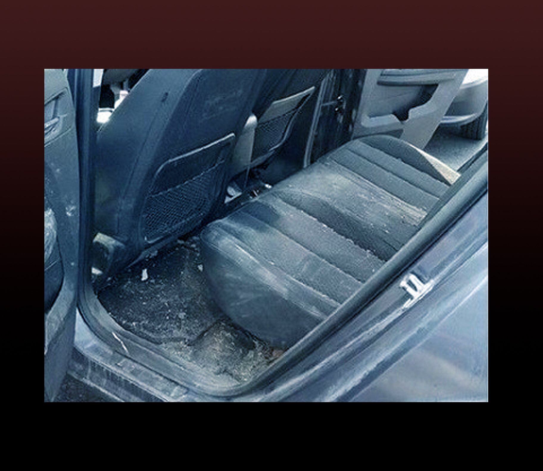 Dirty car interior, rear seat and floor covered in debris.