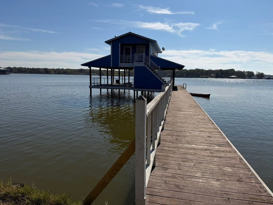 Floating lakeside house beside a wooden dock under a blue sky