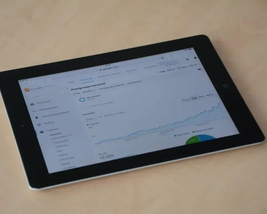 Tablet displaying an analytics dashboard with a rising line graph on a desk