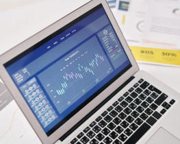 Laptop displaying a blue stock market chart on a desk with financial documents nearby
