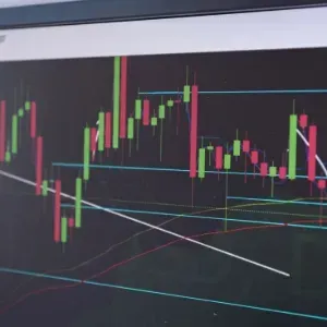 Glowing candlestick stock chart with red and green bars and trend lines on a dark screen