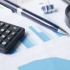 Calculator, pen, and blue bar chart on a financial report
