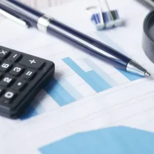 Calculator, pen, and blue bar chart on a financial report