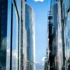 Modern glass office towers lining a narrow street under a blue sky