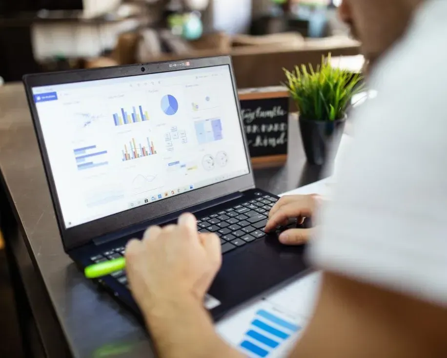 Person working on a laptop with analytics charts on screen in a desk workspace