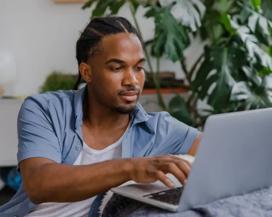 Person using a laptop on a couch in a bright living room