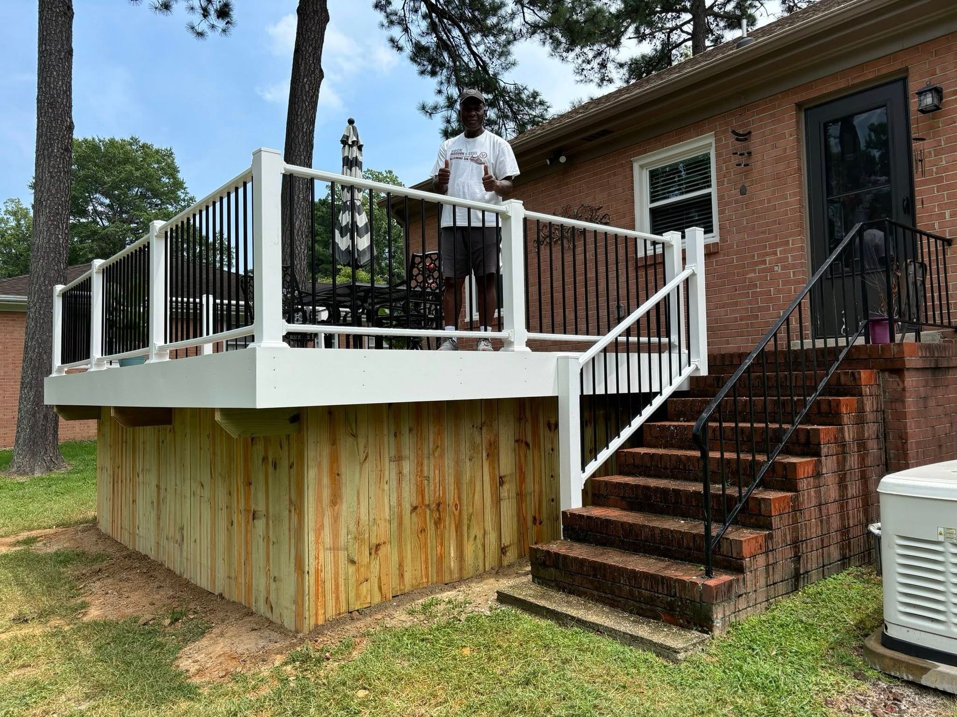 Raised white deck attached to brick house, with stairs and a person standing on the porch.