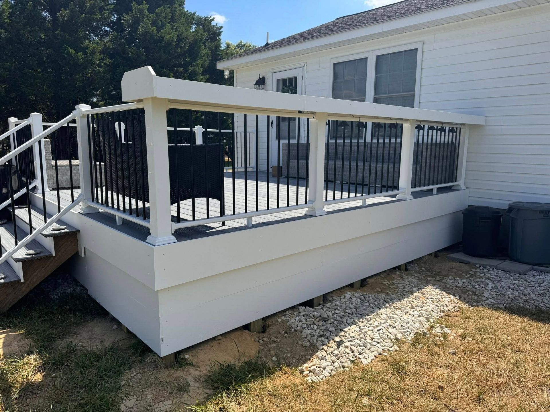 White accessible deck with ramp and black railing beside a house