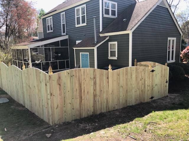 Dark blue house with a newly built light wood fence around the backyard.
