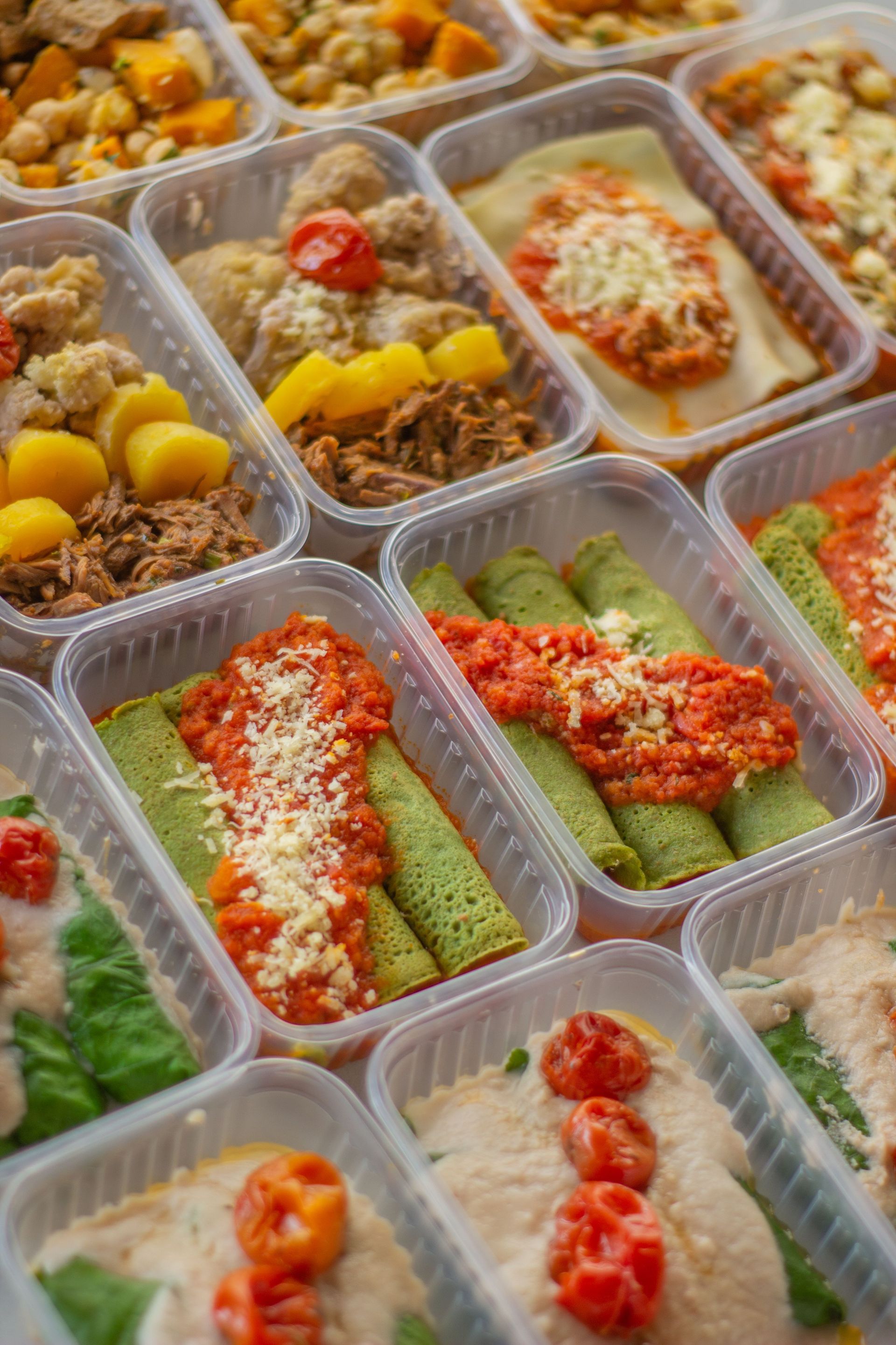 Meal-prep containers with veggie and chicken dishes topped with red sauce