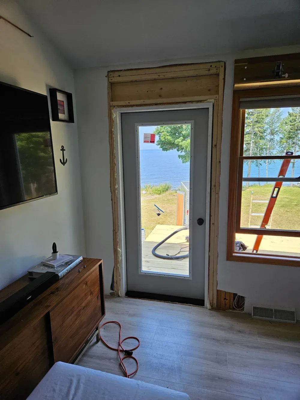 Bright room with glass door to a lake view, window, wood floor, and TV stand