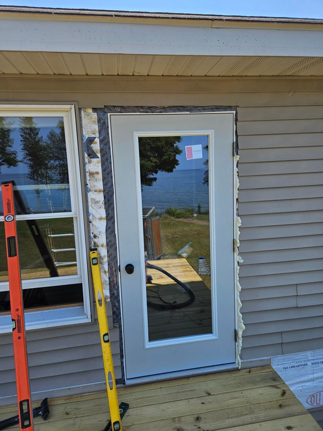 House exterior with a white storm door, adjacent window, and ladder leaning beside the entryway