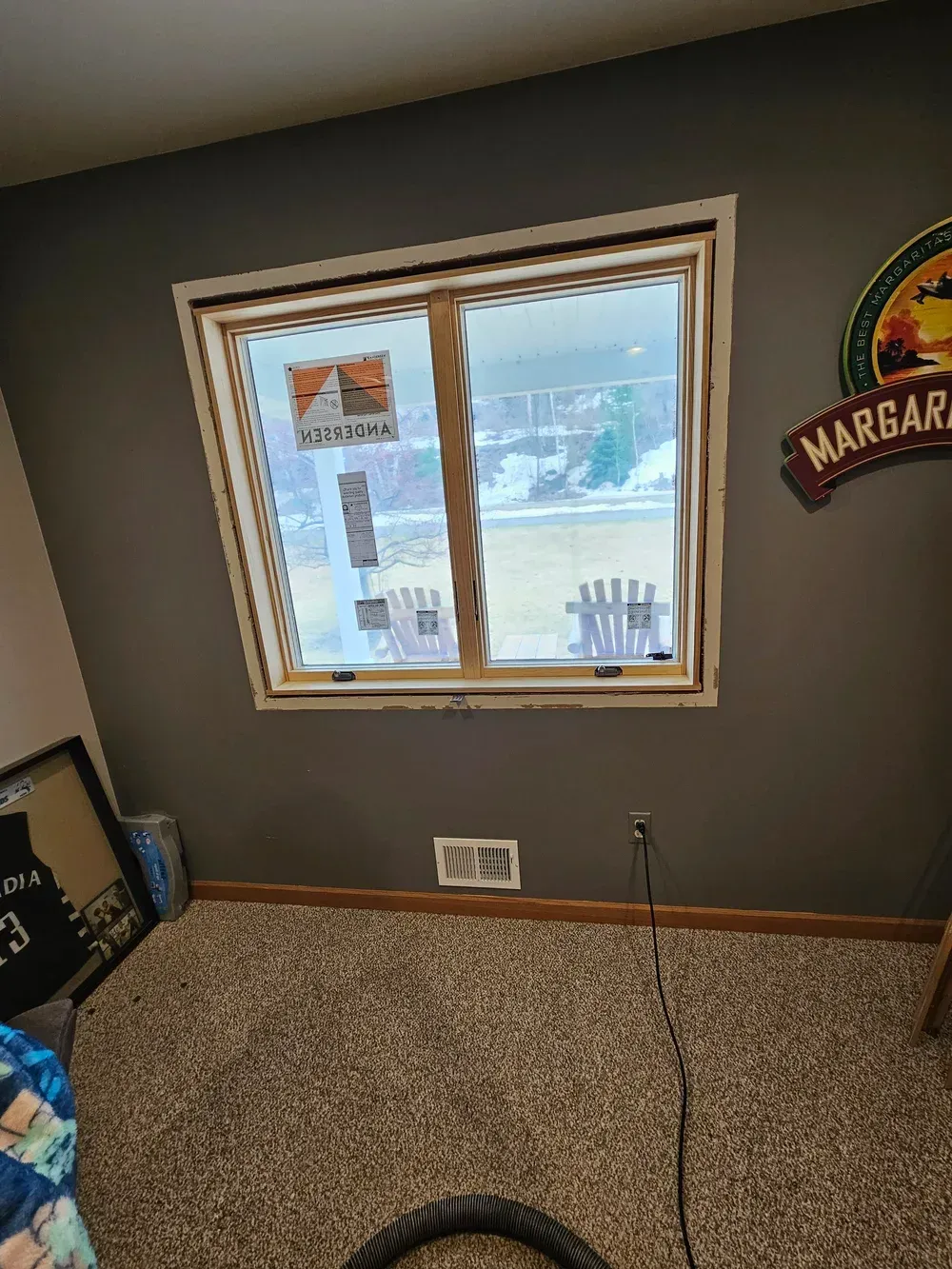 Empty carpeted room with a window, gray walls, and a loose cable on the floor.