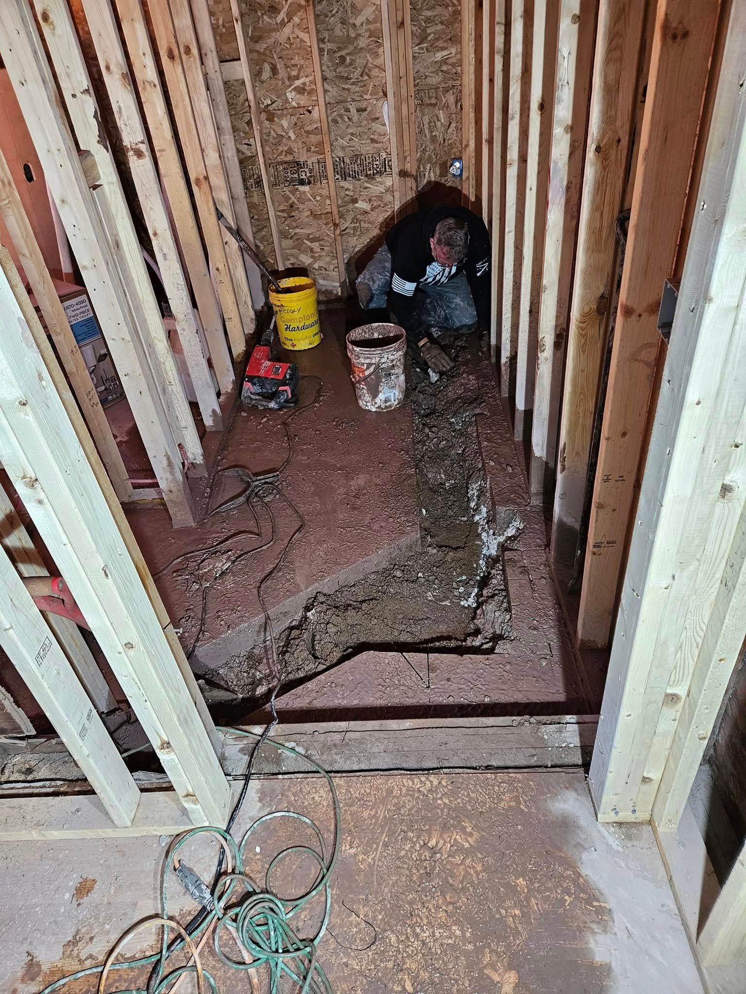 Partially framed room with debris, tools, and a narrow dirt path between wall studs