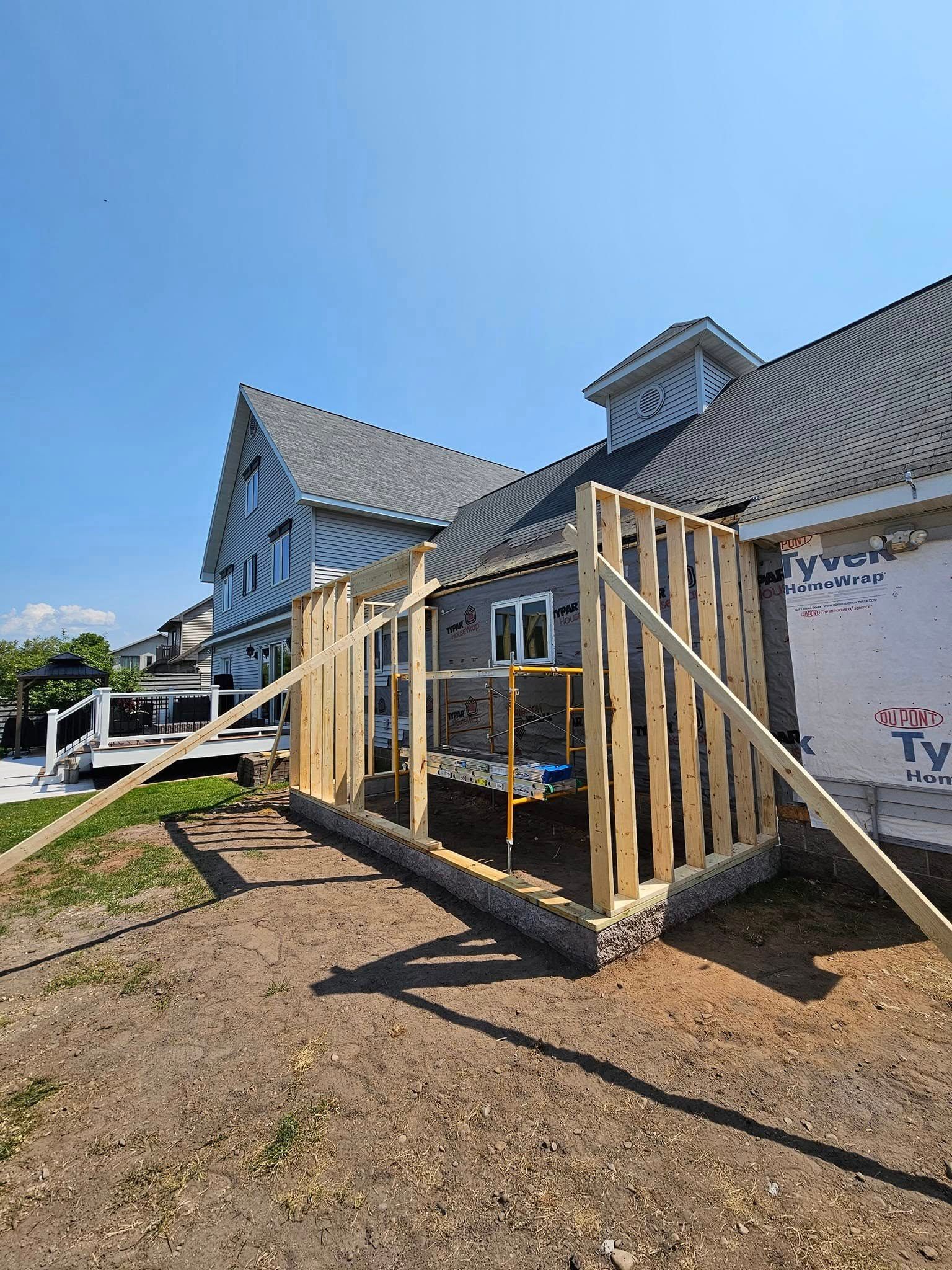House under construction with wooden framing around a porch on a sunny day