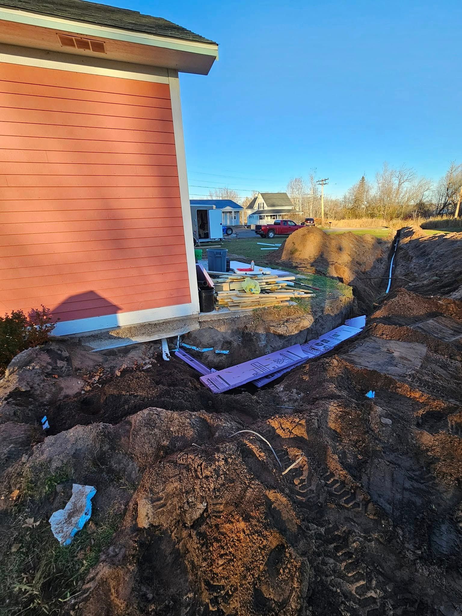 Backyard dirt trench beside a brick house, with a purple tarp and scattered debris.