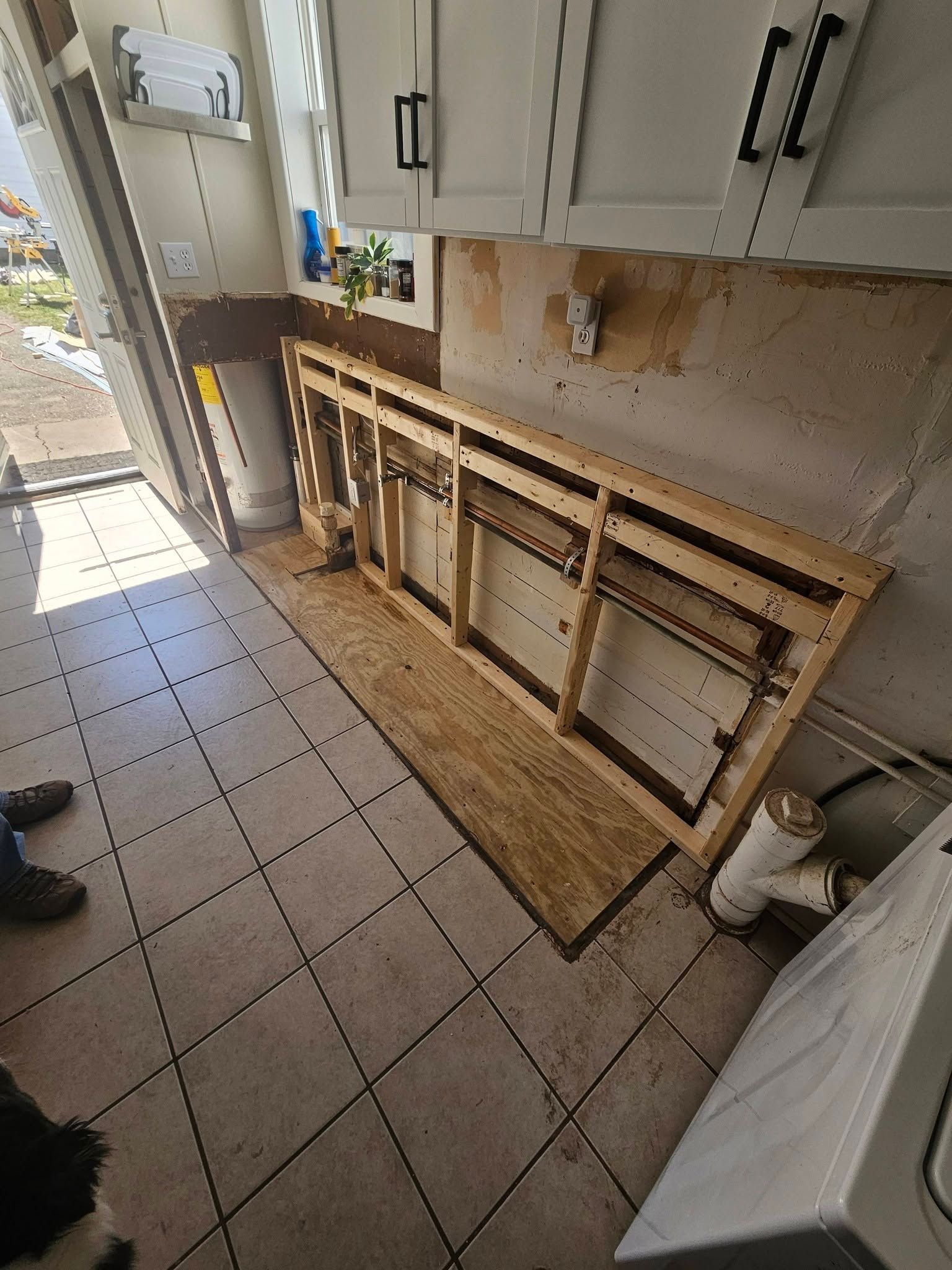 Kitchen with a missing cabinet and exposed wall framing beneath the countertop.