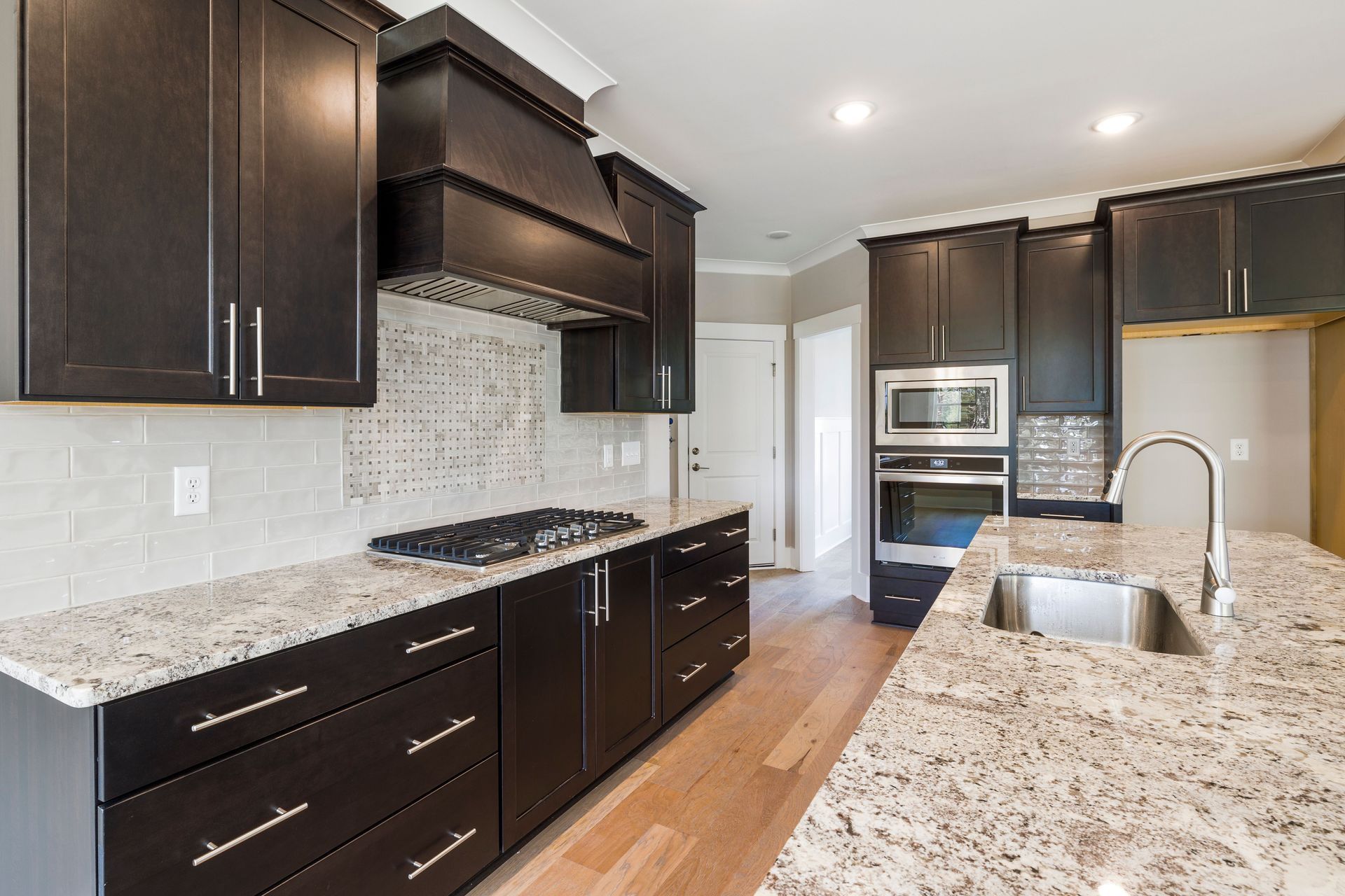 Modern kitchen with dark cabinets, granite countertops, stainless appliances, and hardwood floors