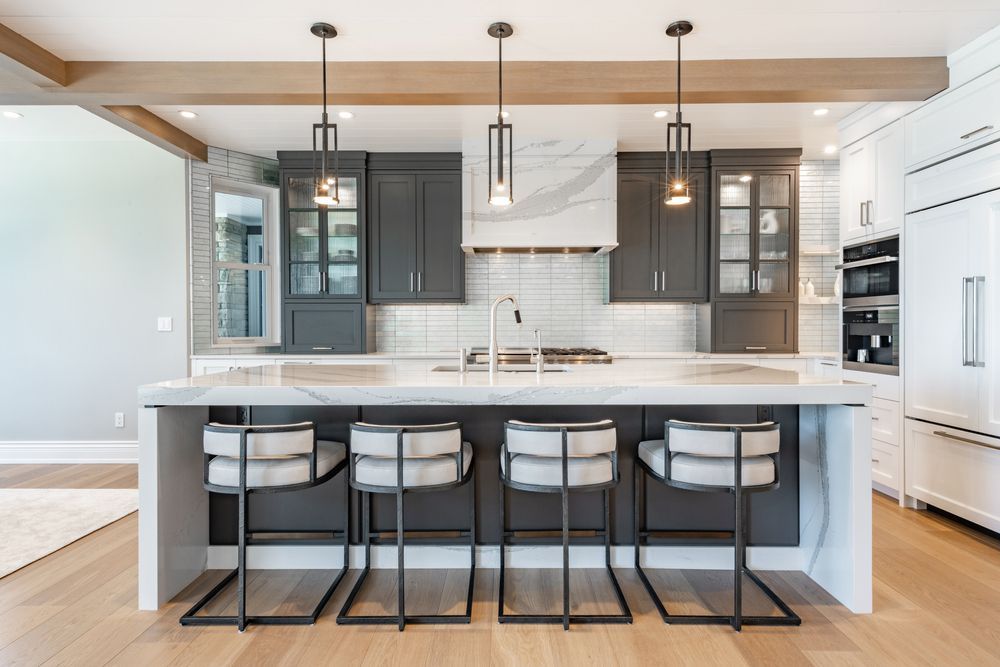Modern kitchen with gray cabinets, white island, pendant lights, and four bar stools