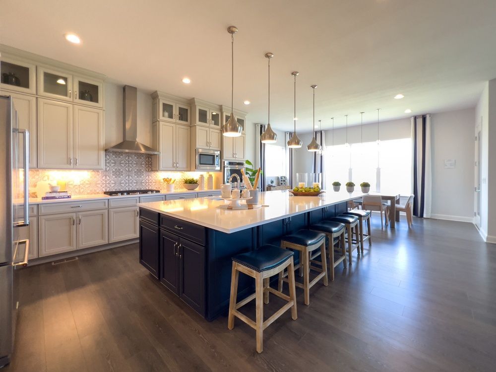 Modern kitchen with a large island, pendant lights, and stools, in a bright open-concept room