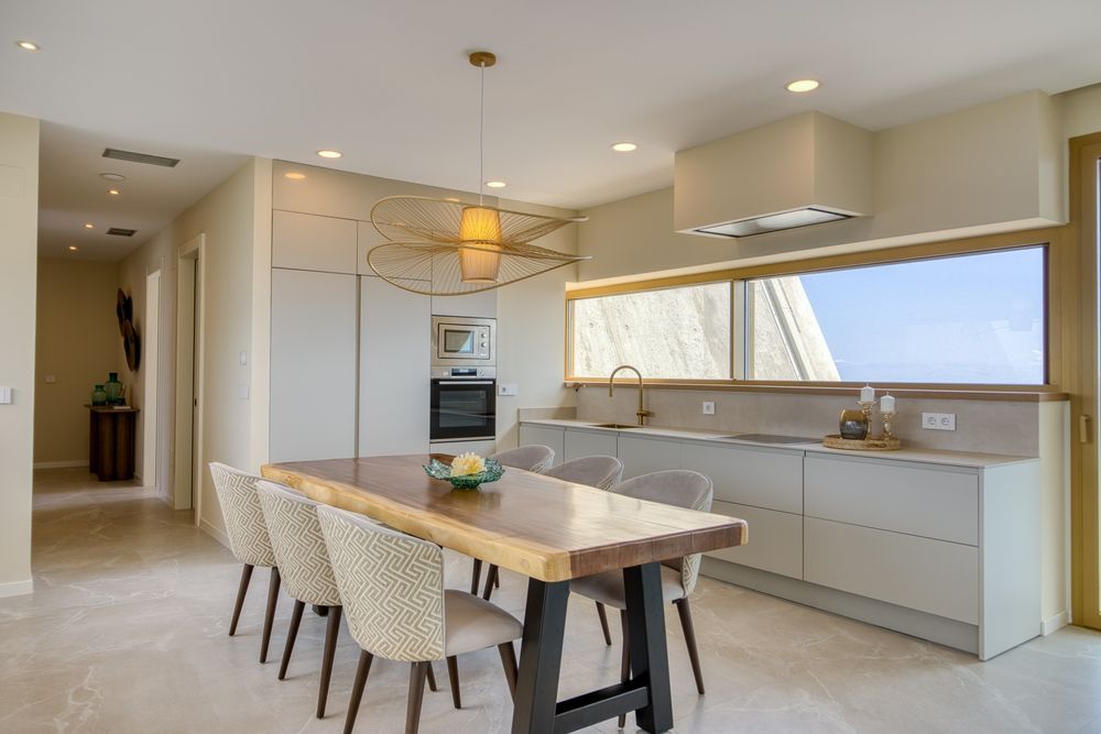 Modern kitchen with island, long window, and built-in appliances, shown in warm neutral tones