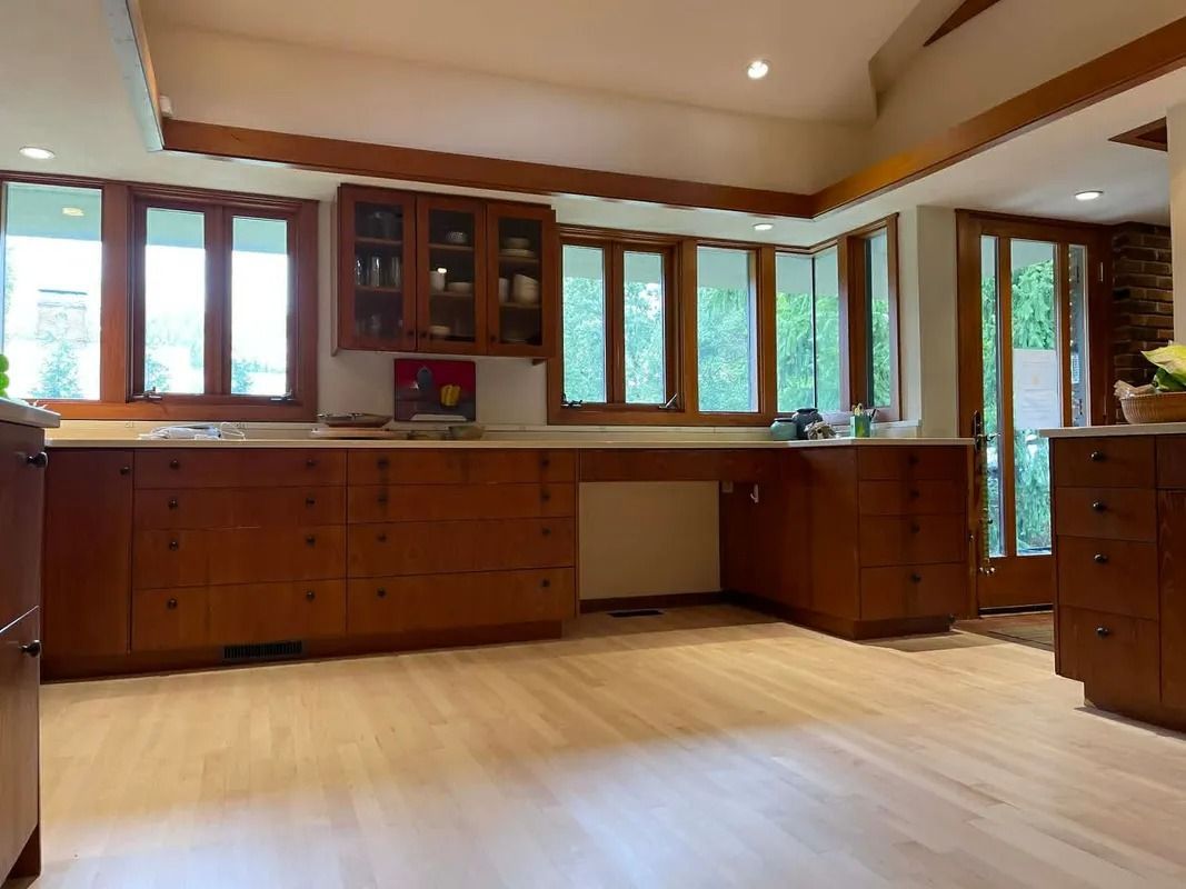 Spacious kitchen with wooden cabinets, light wood floor, and large windows letting in natural light