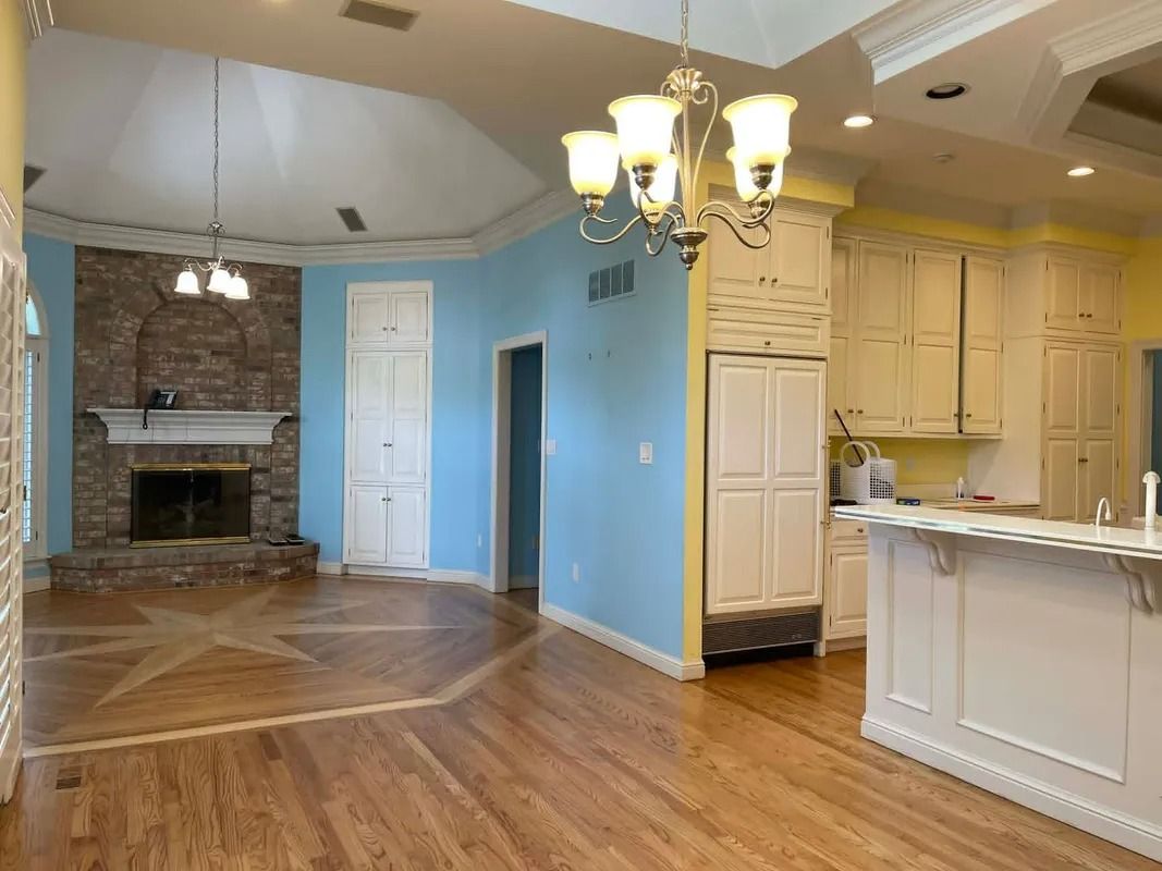 Spacious open-concept kitchen and living area with hardwood floors, white cabinets, fireplace, and blue walls