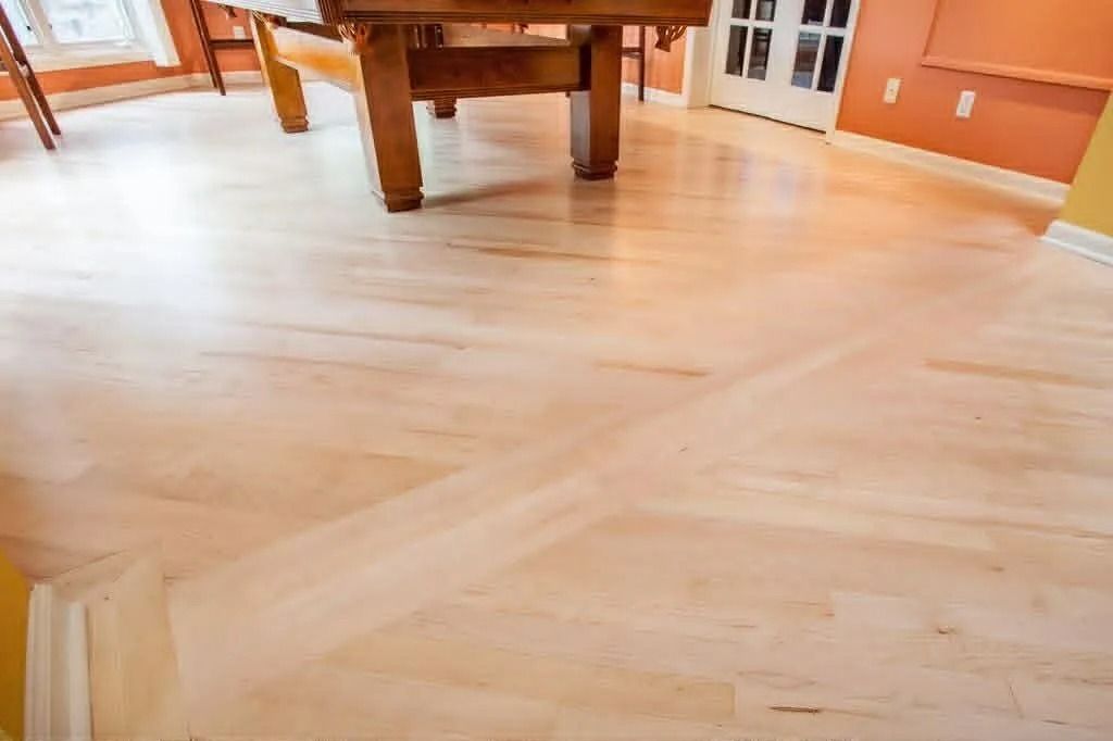 Light wood floor in a bright room with a wooden table and orange walls