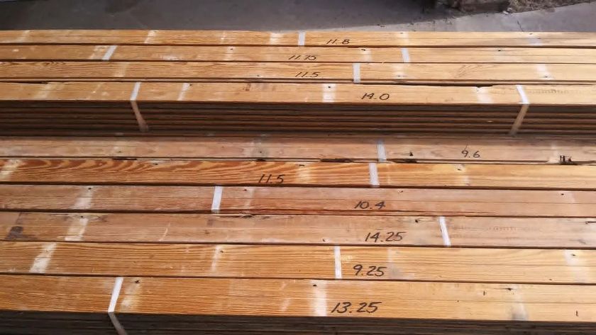 Stacked wooden planks with handwritten measurements marked on the boards