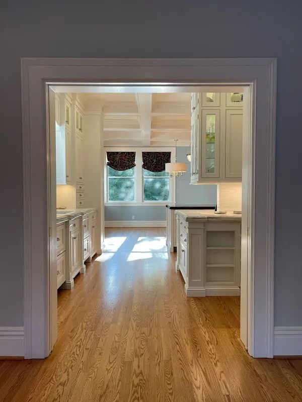 Bright kitchen with white cabinets, hardwood floors, and a sunlit windowed alcove
