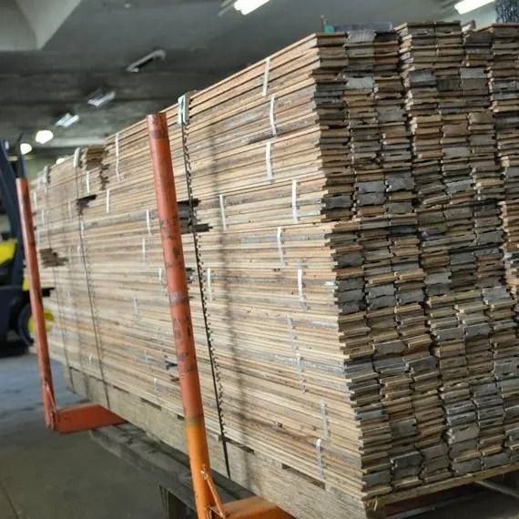 Stacked cardboard sheets on a pallet in an industrial warehouse, secured by orange straps