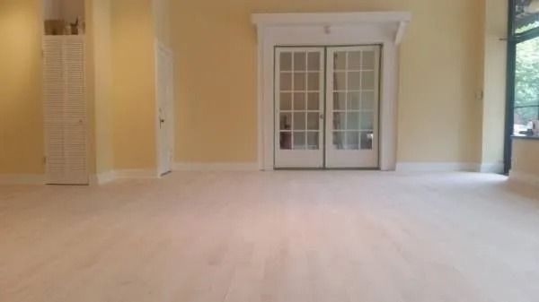 Empty beige room with light wood floor and French doors centered on the far wall