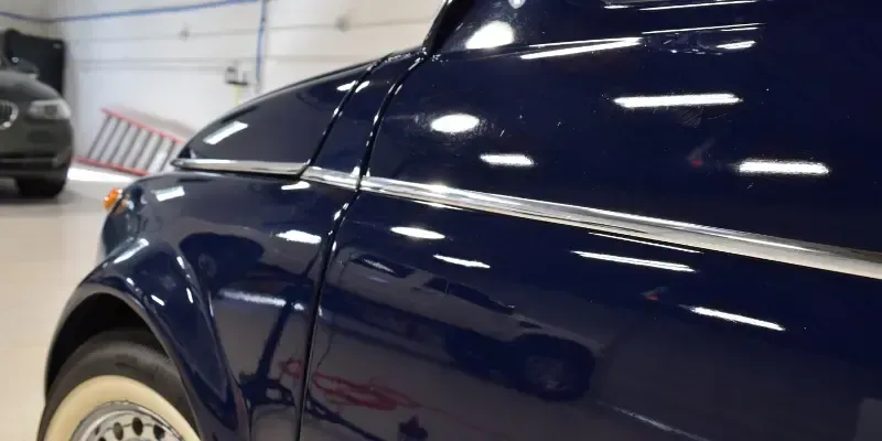 A blue car with white tires is parked in a garage.