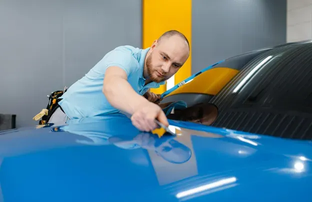 A man is working on a blue car in a garage.