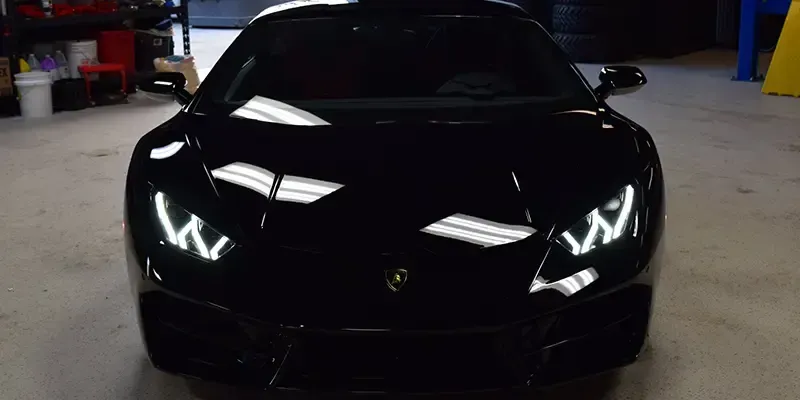 A black lamborghini huracan is parked in a garage.