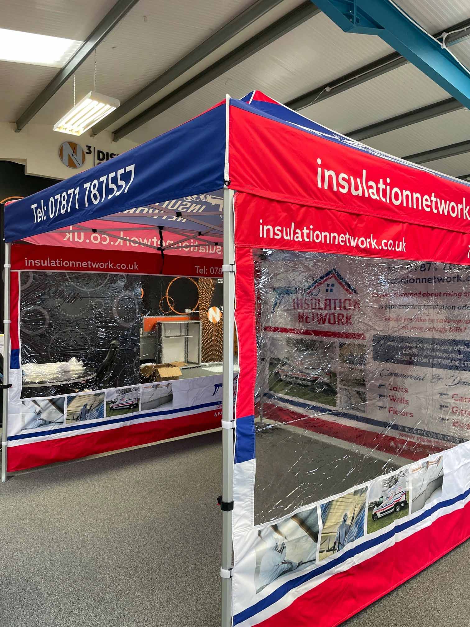 A red , white and blue tent is sitting in a room.