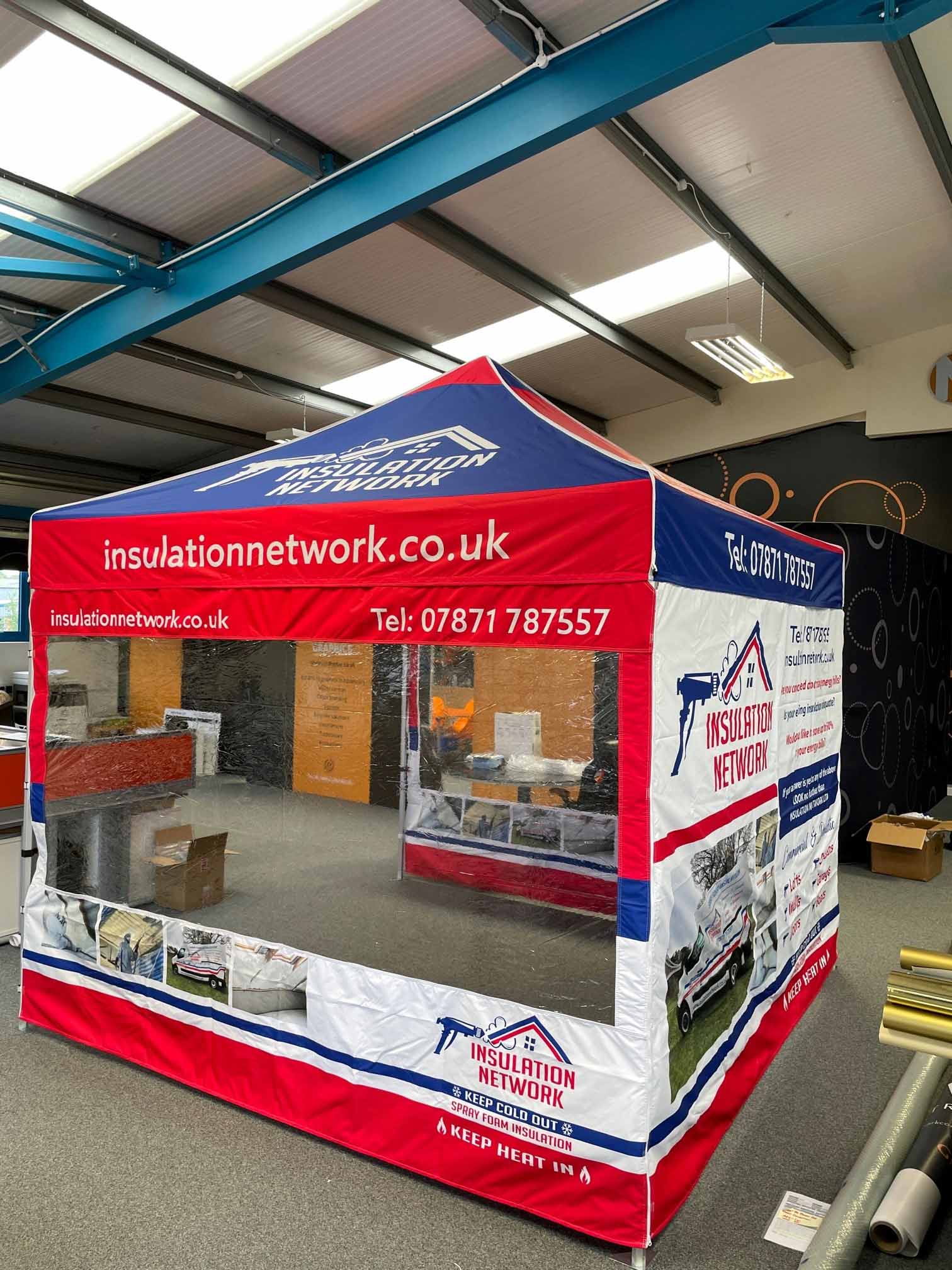 A red , white and blue tent is sitting in a room.