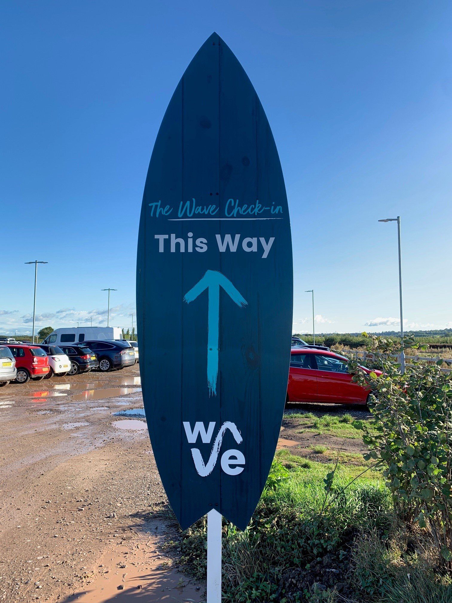 A sign in the shape of a surfboard shows the way to the wave check in.