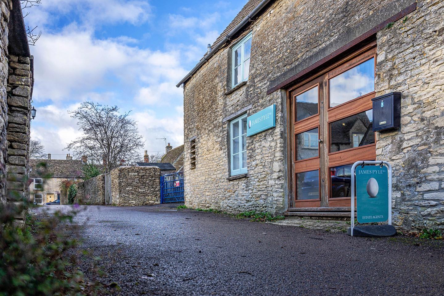 A stone building with a wooden door and a sign in front of it.
