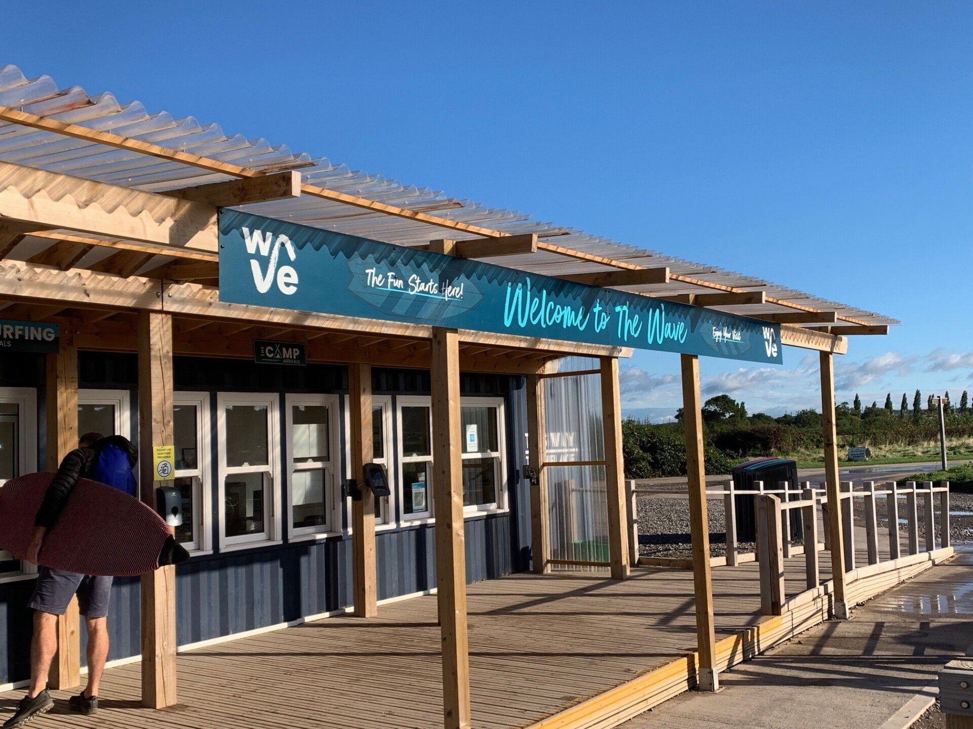 A person is standing in front of a building with a sign that says welcome.