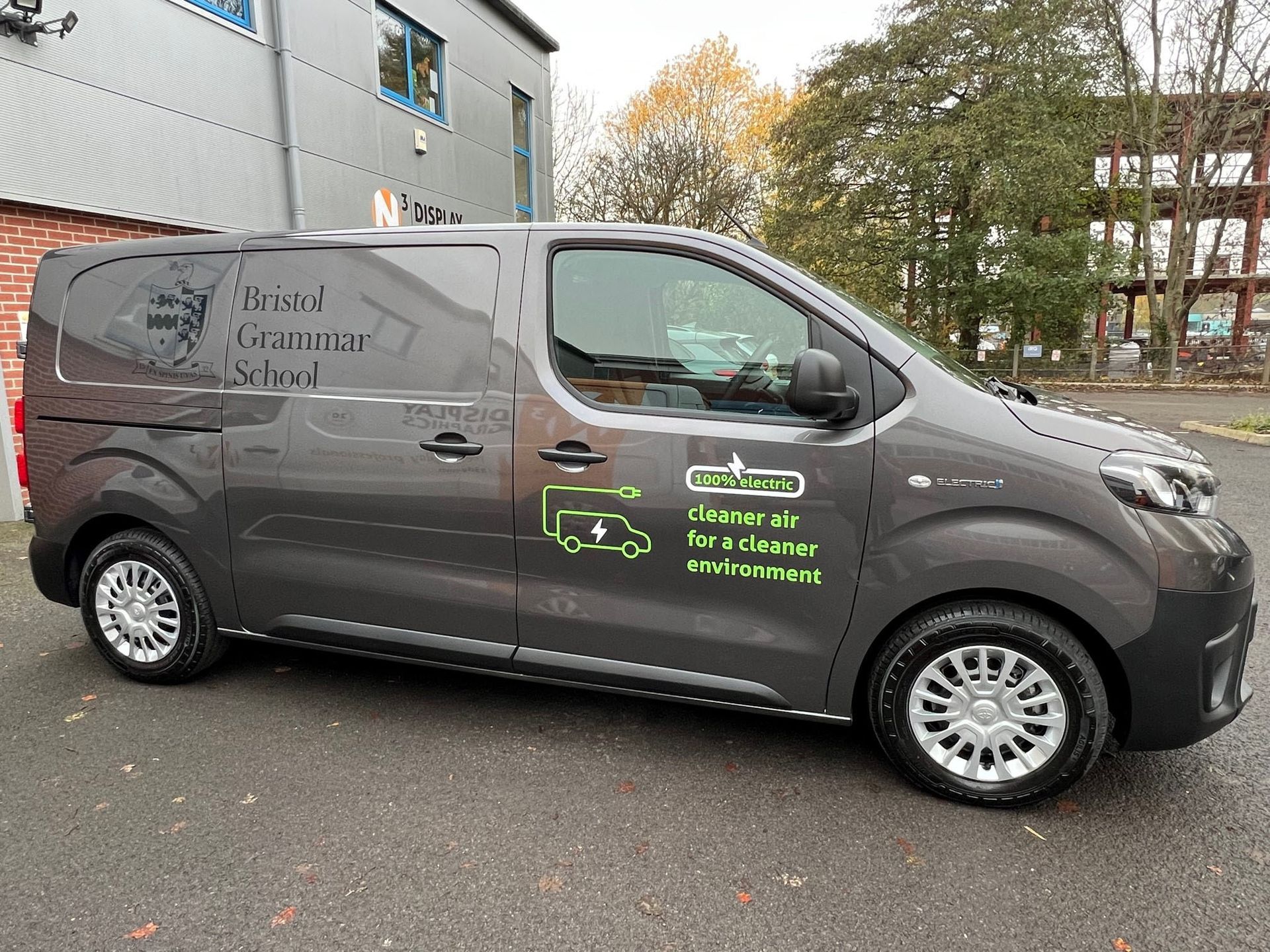 A grey van is parked in front of a building.