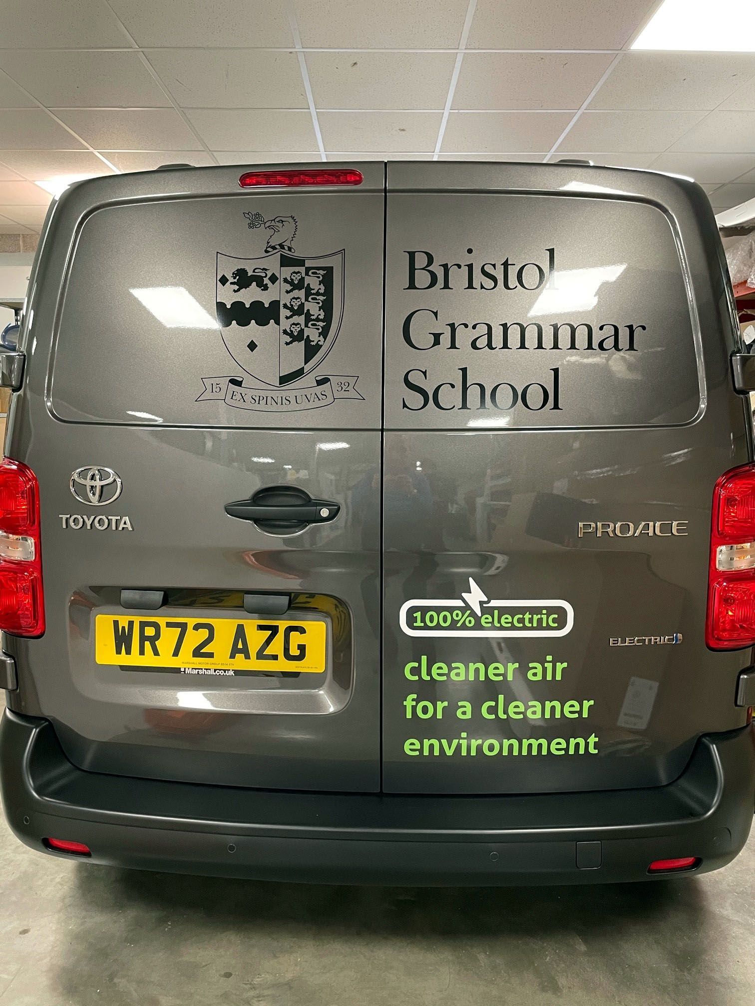 A toyota van is parked in a garage with a sticker on the back window that says bristol grammar school.