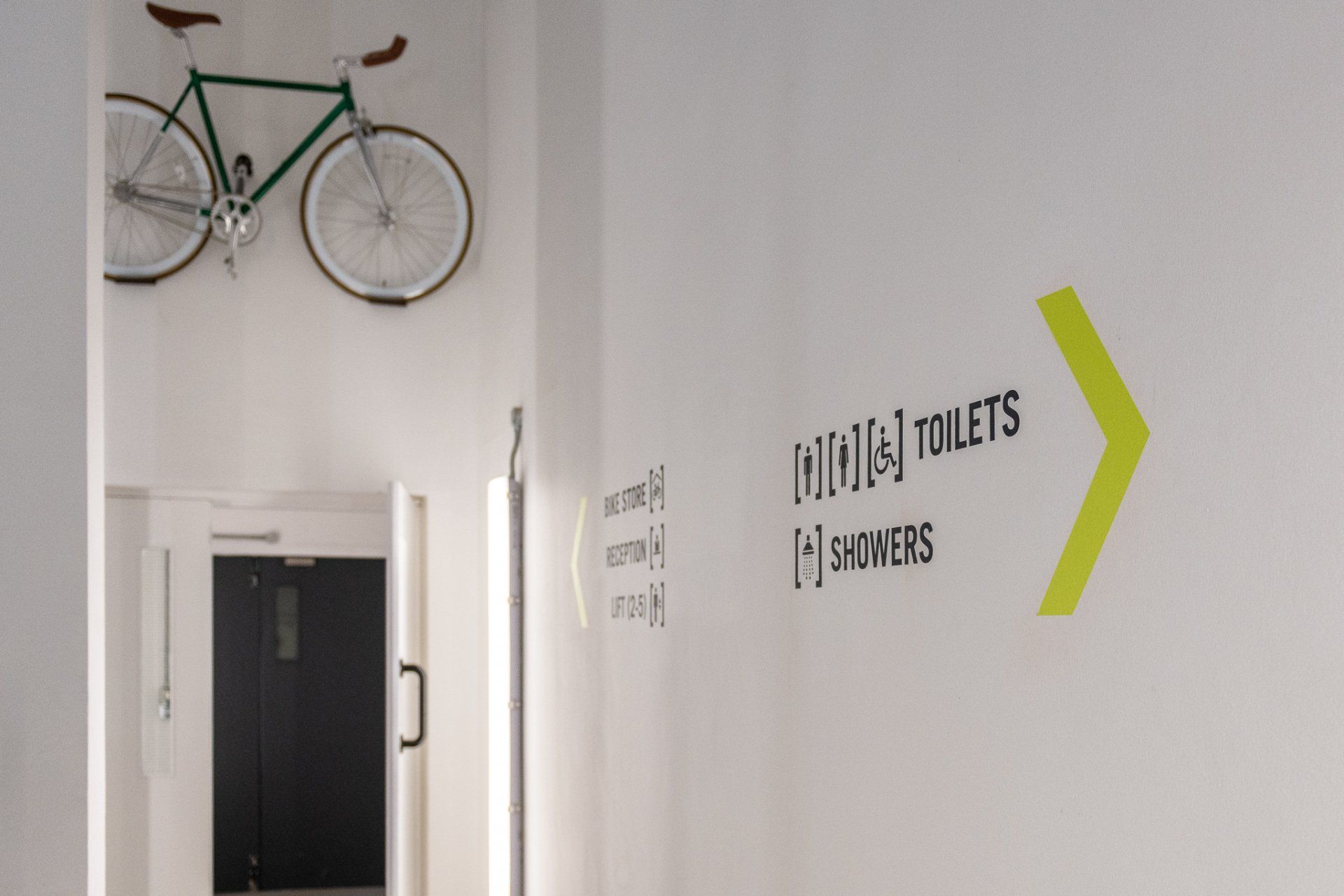 A bicycle is hanging on a wall next to a sign that says toilets and showers